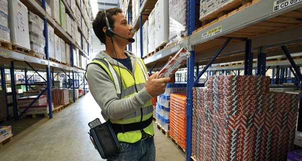 A worker uses a voice-directed picking solution to fill orders